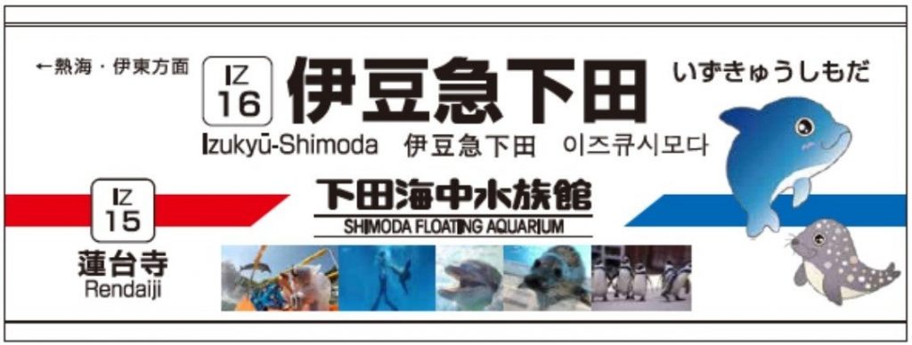 「下田海中水族館」の副駅名が書かれた、伊豆急下田駅の駅名表示板画像。イルカのイラストやペンギンなどの写真も描かれている。